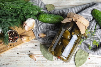 Flat lay composition with jar of pickled cucumbers on white wooden table