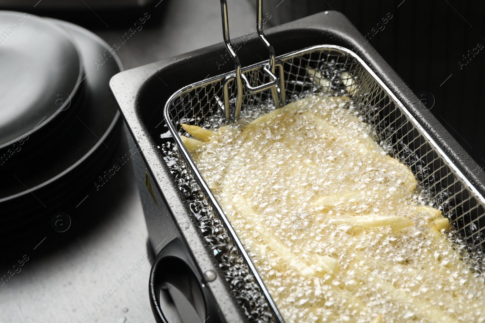 Photo of Cooking delicious french fries in hot oil, closeup