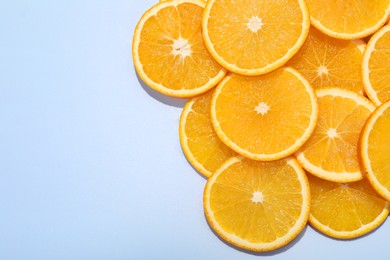 Photo of Slices of juicy orange on light blue background, top view. Space for text
