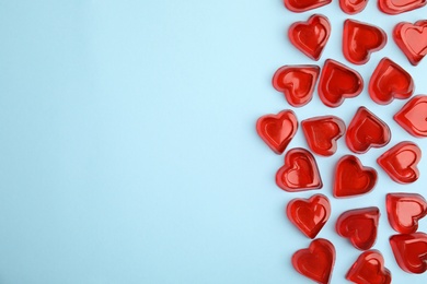 Photo of Sweet heart shaped jelly candies on light blue background, flat lay. Space for text