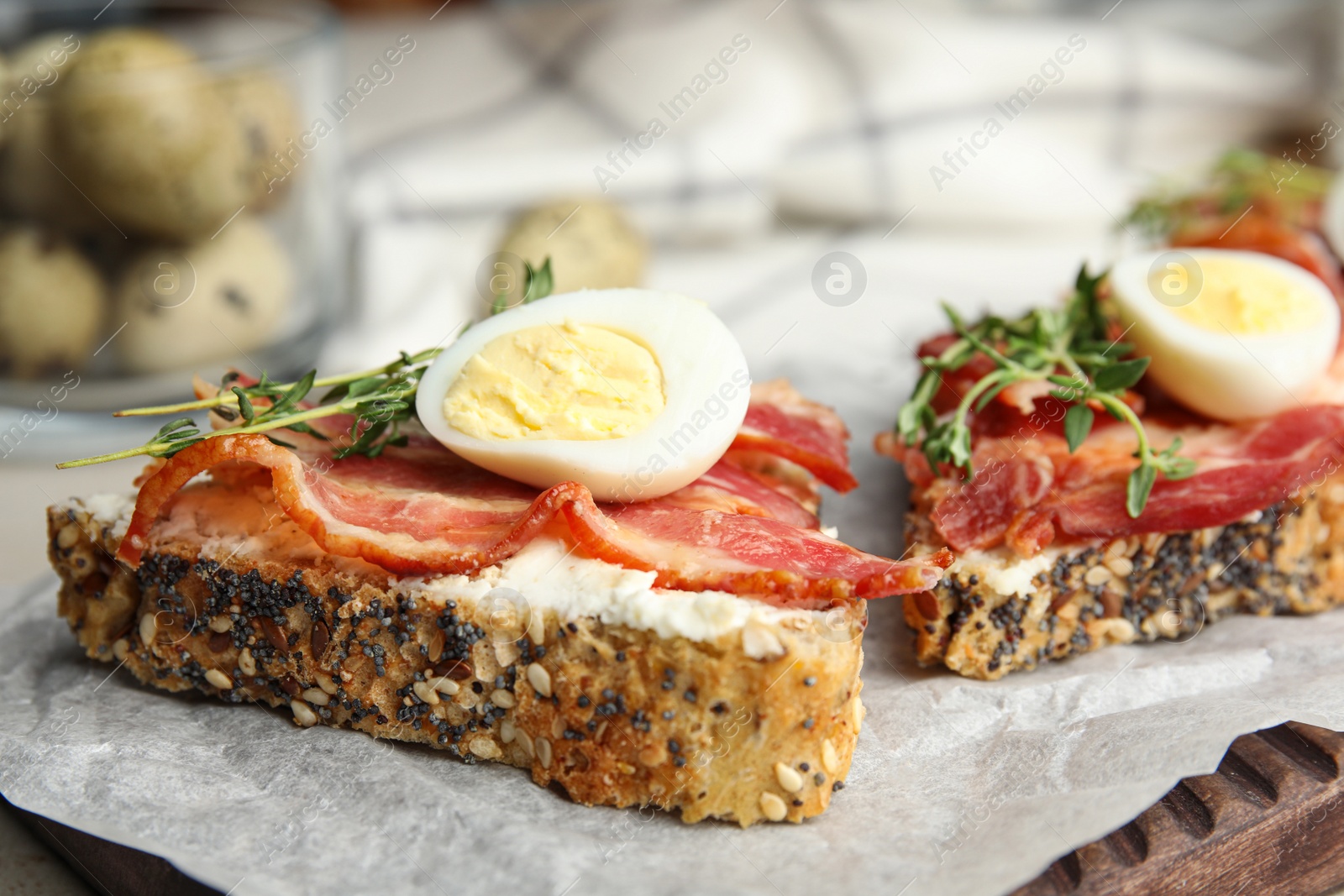 Photo of Cutting board of delicious bruschettas with prosciutto on table, closeup