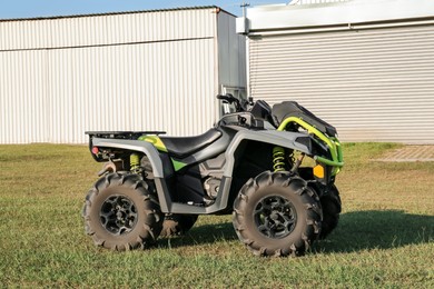 Photo of Modern quad bike in field near hangars on sunny day