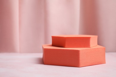 Photo of Orange geometric figures on pink marble table, space for text. Stylish presentation for product