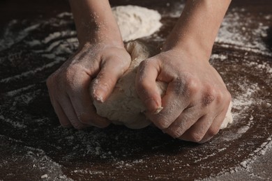 Making bread. Woman kneading dough at wooden table, closeup