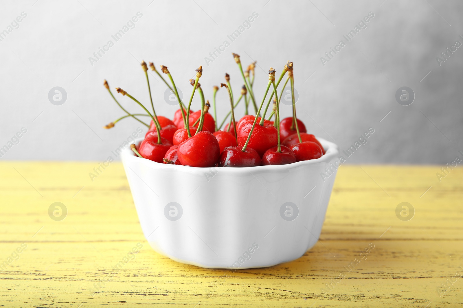 Photo of Bowl with ripe red cherries on wooden table