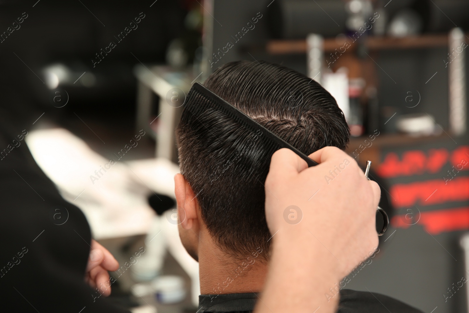 Photo of Professional barber making stylish haircut in salon, closeup