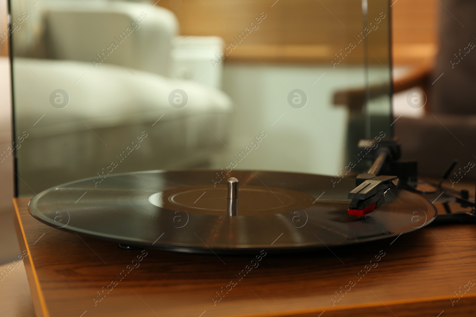 Photo of Modern vinyl record player with disc on table indoors, closeup