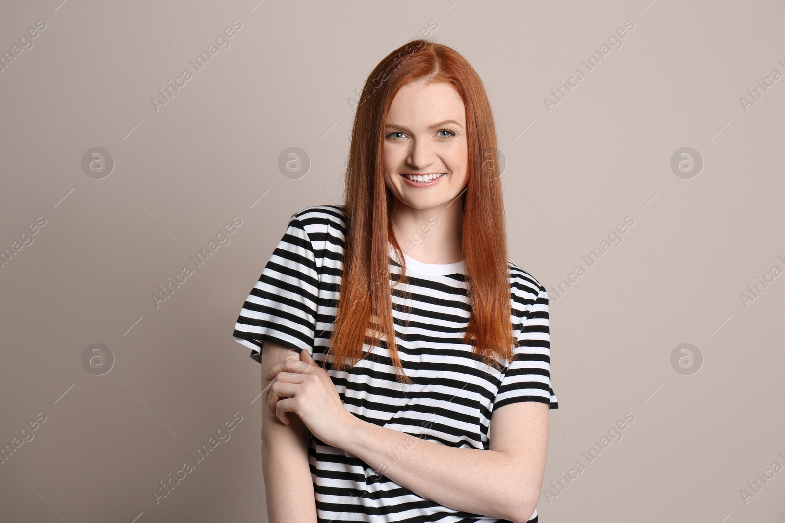 Photo of Candid portrait of happy young woman with charming smile and gorgeous red hair on beige background