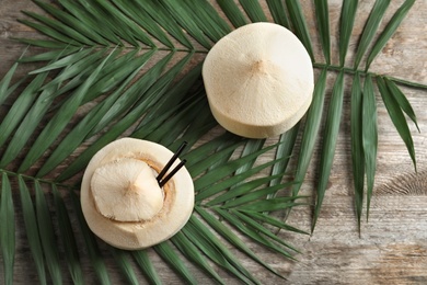 Fresh coconut drink and leaves on wooden background