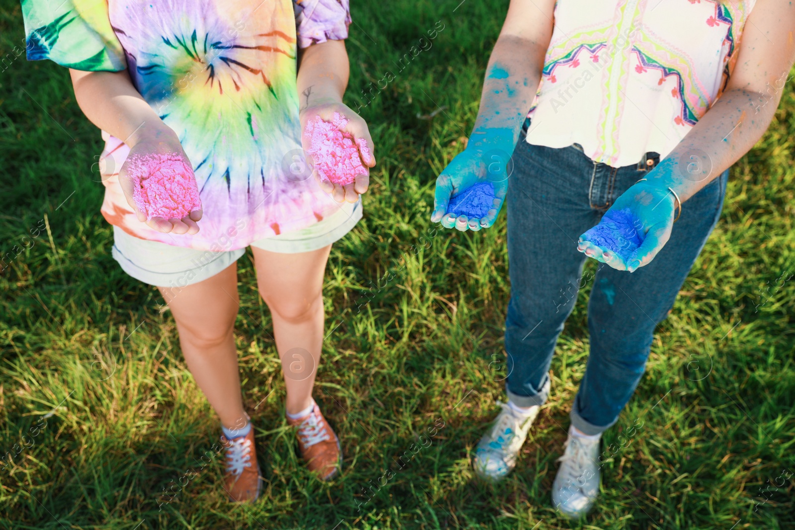 Photo of Women with colorful powder dyes outdoors, closeup. Holi festival celebration