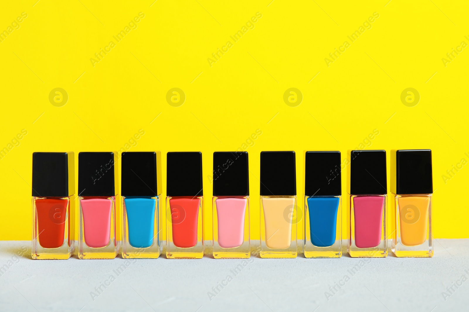 Photo of Bright nail polishes on table against color background. Space for text