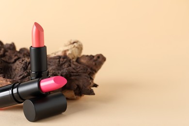 Beautiful pink lipsticks on beige background, space for text