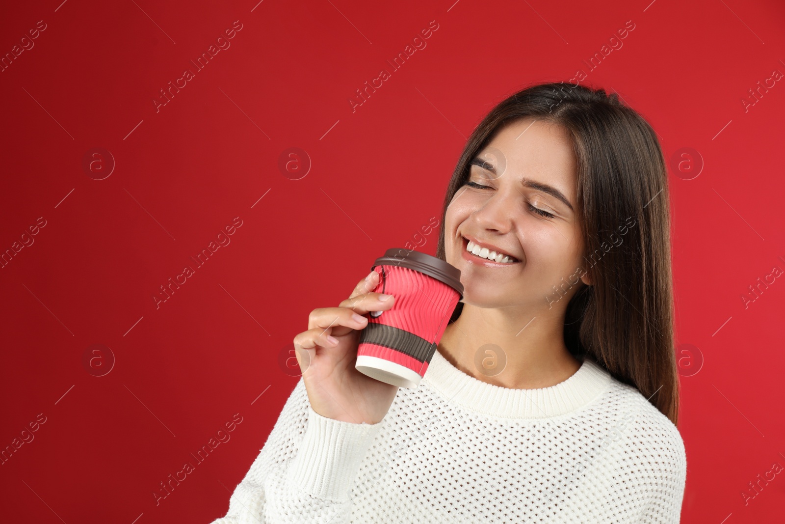 Photo of Happy beautiful woman with paper cup of mulled wine on red background. Space for text