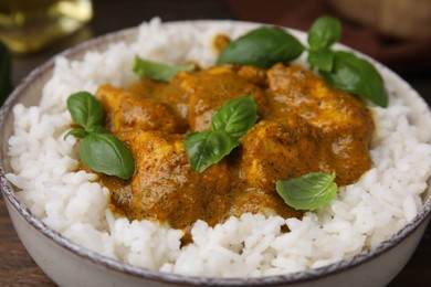 Photo of Delicious rice and chicken with curry sauce in bowl, closeup