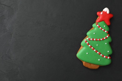 Photo of Christmas tree shaped cookie on black table, top view. Space for text
