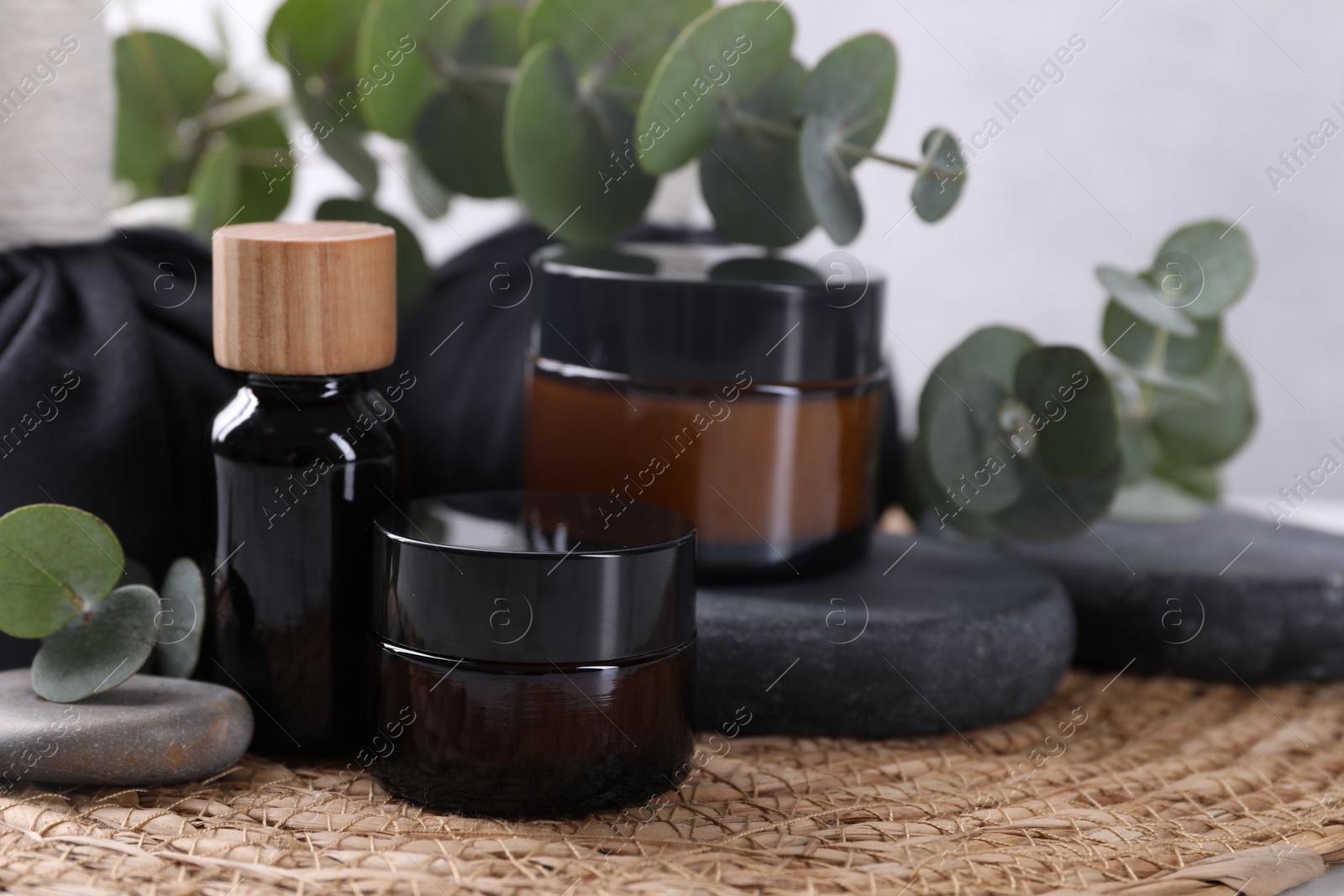 Photo of Spa composition with cosmetic products, stones and eucalyptus branches on table