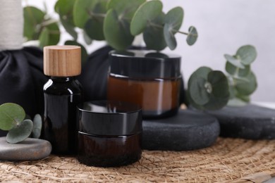 Spa composition with cosmetic products, stones and eucalyptus branches on table