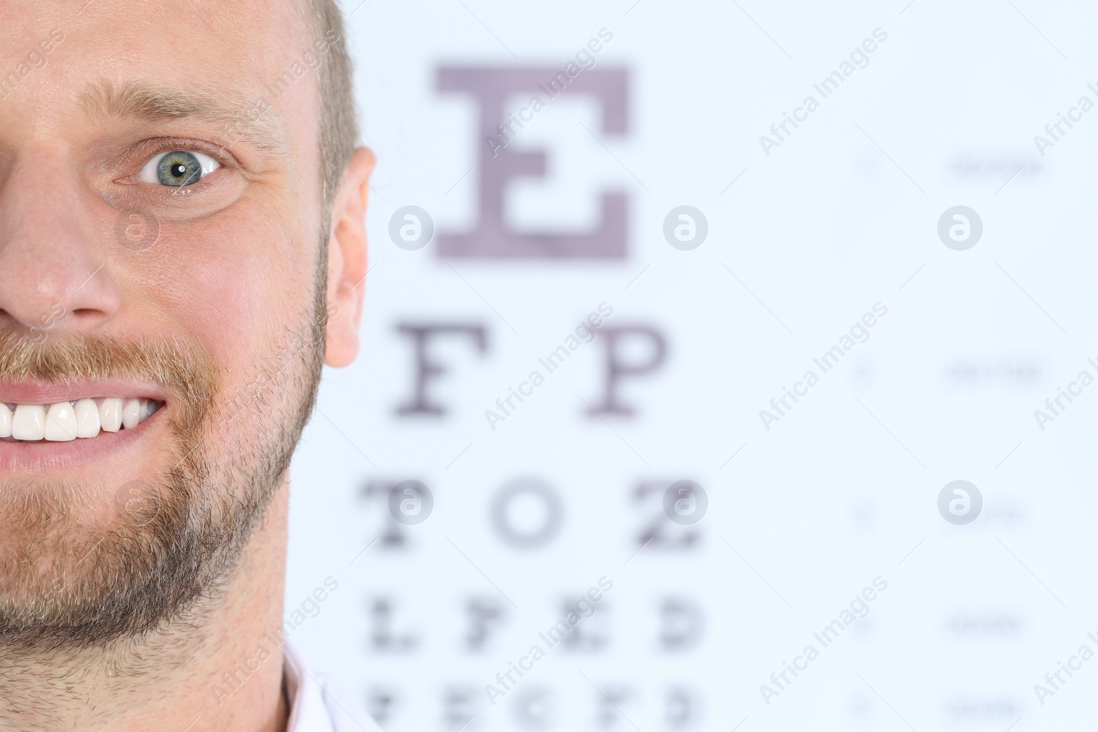 Photo of Closeup view of man and blurred eye chart on background. Space for text