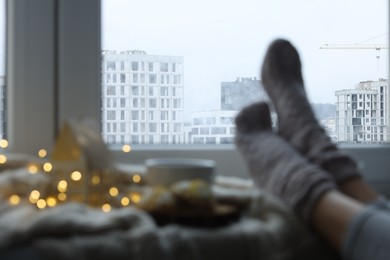 Photo of Woman enjoying city view by window, closeup. Selective focus