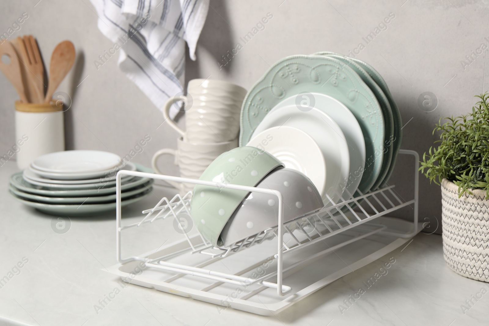 Photo of Many different clean dishware and houseplant on white table indoors