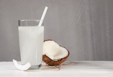 Glass of coconut water and nut on white wooden table. Space for text