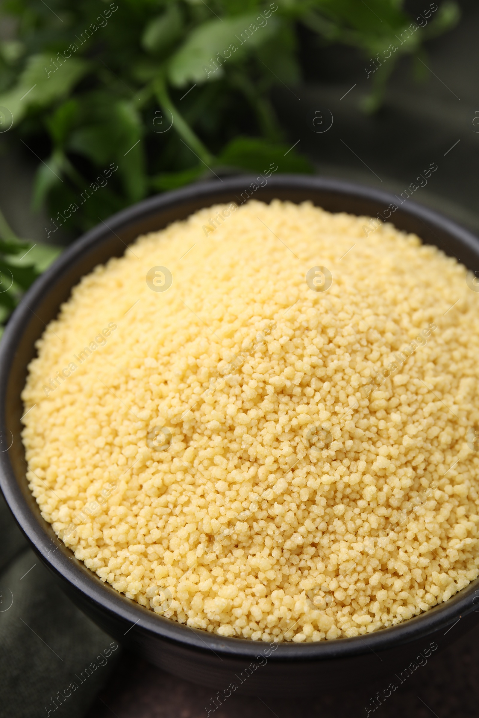 Photo of Raw couscous in bowl on table, closeup