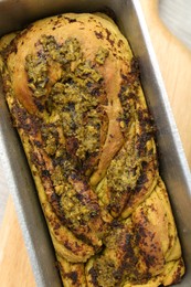 Freshly baked pesto bread in loaf pan on table, top view