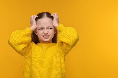 Photo of Little girl suffering from headache on yellow background. Space for text