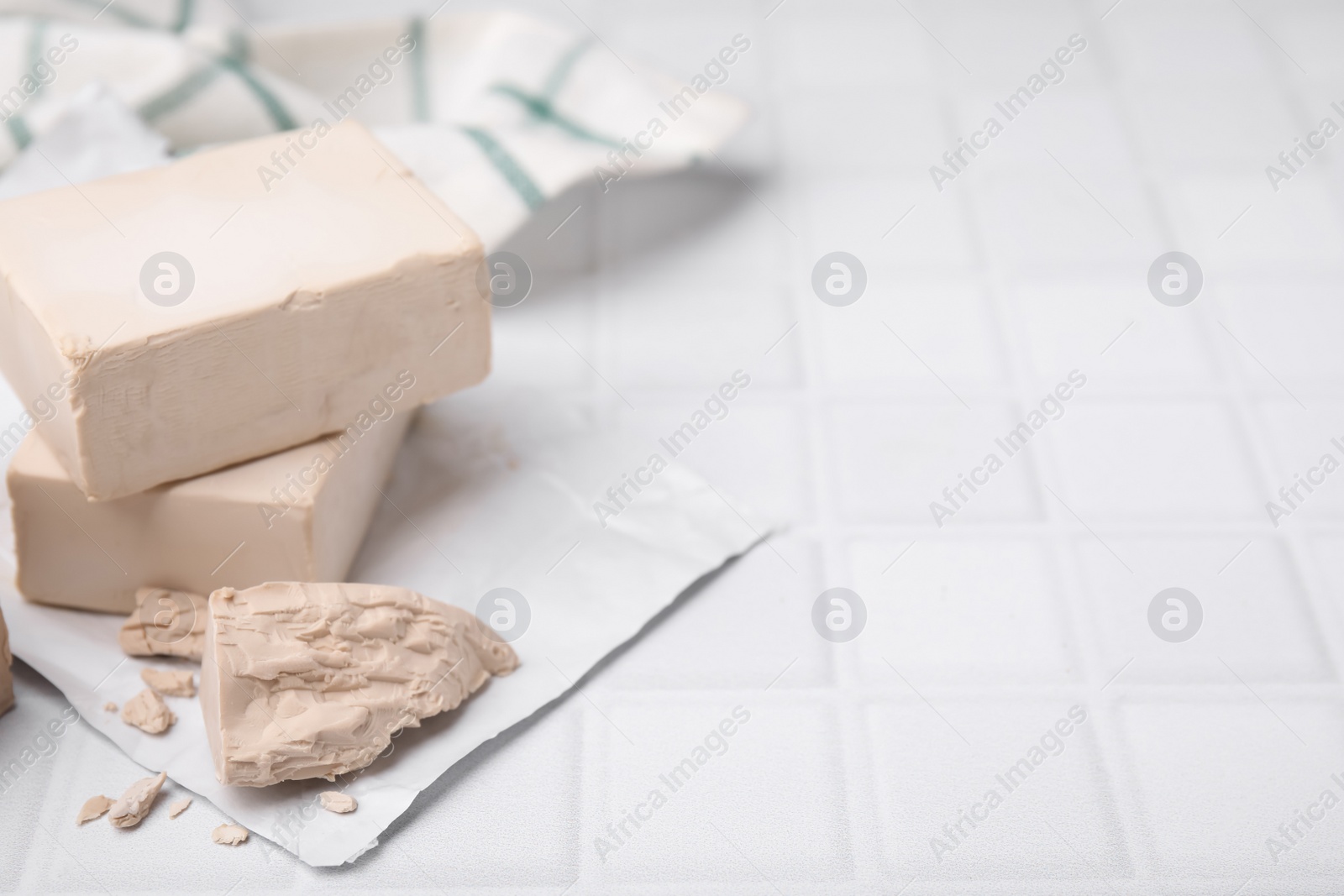 Photo of Blocks of compressed yeast on white table, space for text