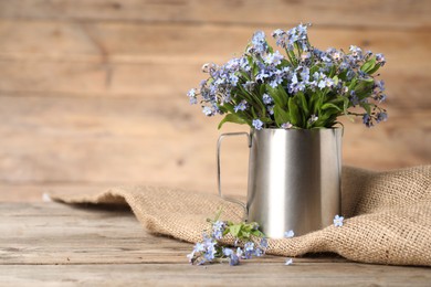 Photo of Beautiful forget-me-not flowers on wooden table, closeup. Space for text