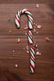 Photo of Broken sweet Christmas candy cane on wooden table, top view