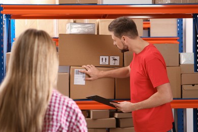 Woman and worker with clipboard near rack at post office