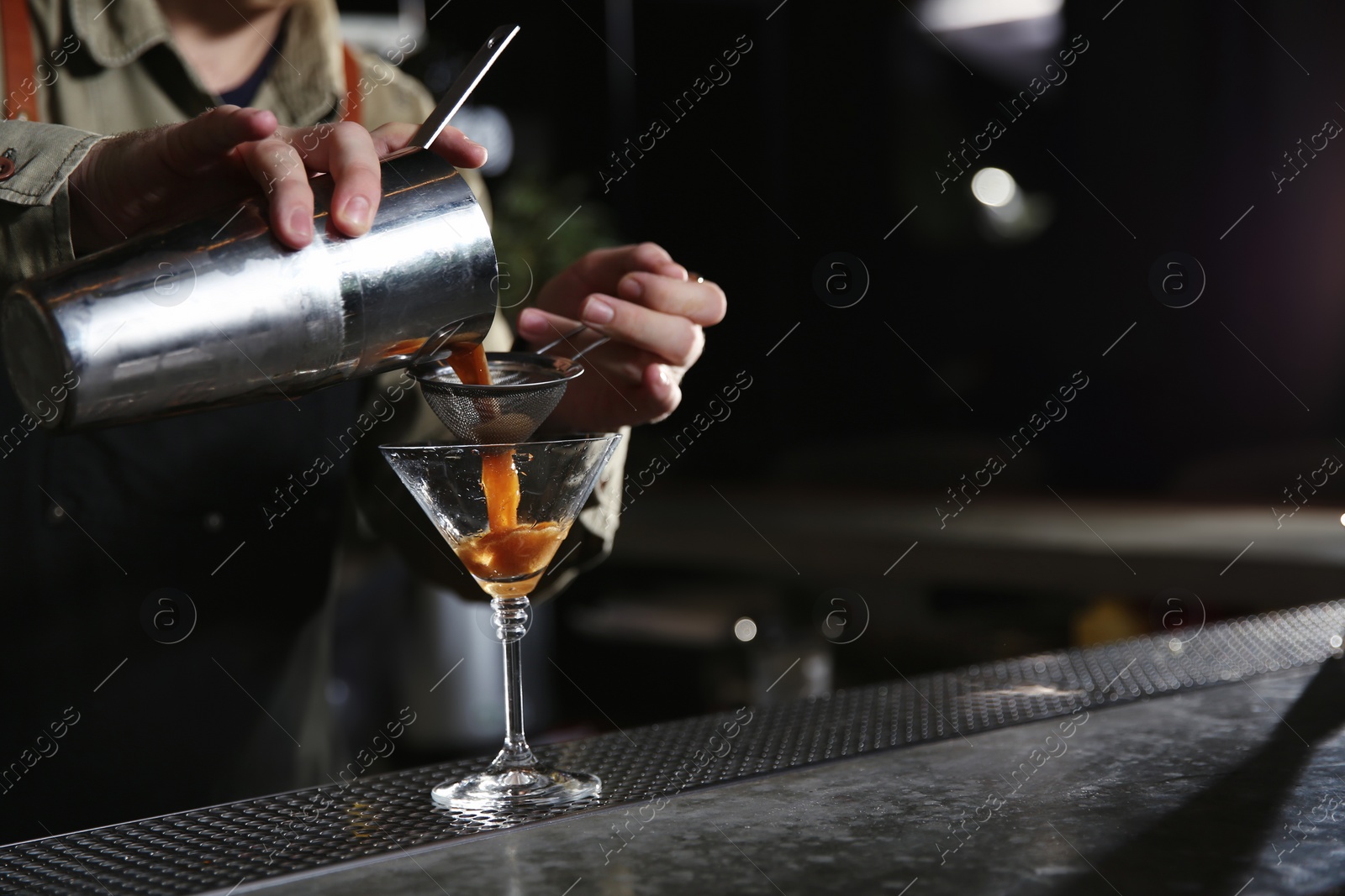 Photo of Barman pouring martini espresso cocktail into glass at counter, closeup. Space for text