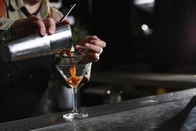 Photo of Barman pouring martini espresso cocktail into glass at counter, closeup. Space for text