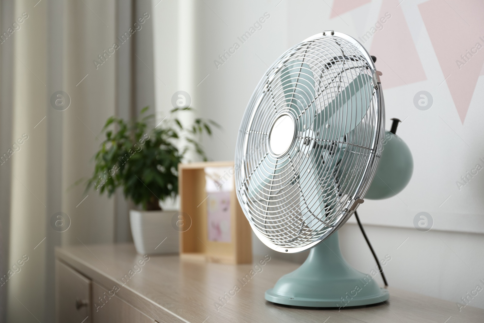 Photo of Modern electric fan on wooden table indoors, space for text. Summer heat