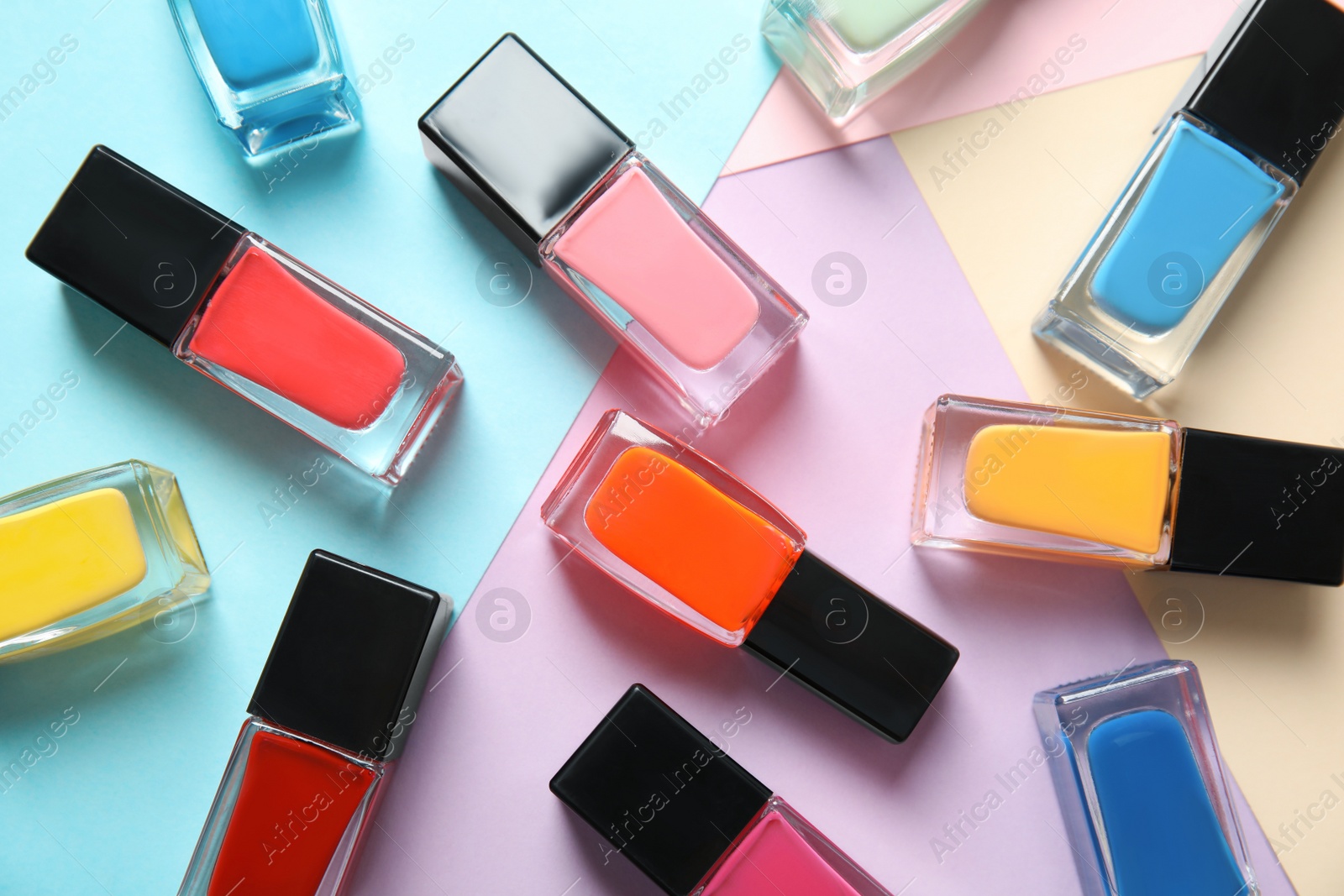 Photo of Bottles of nail polish on color background, top view