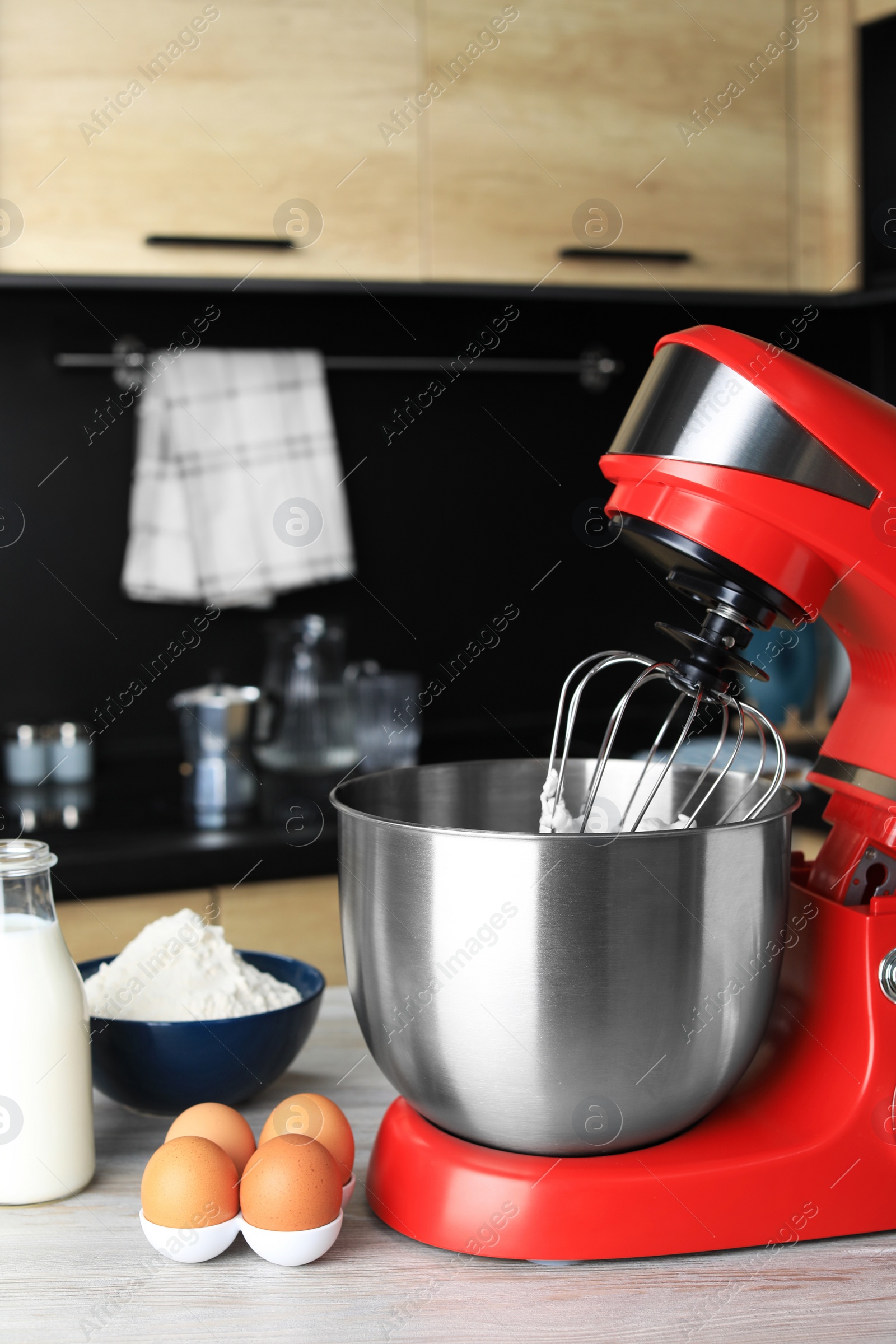 Photo of Modern stand mixer and ingredients on wooden table in kitchen. Home appliance