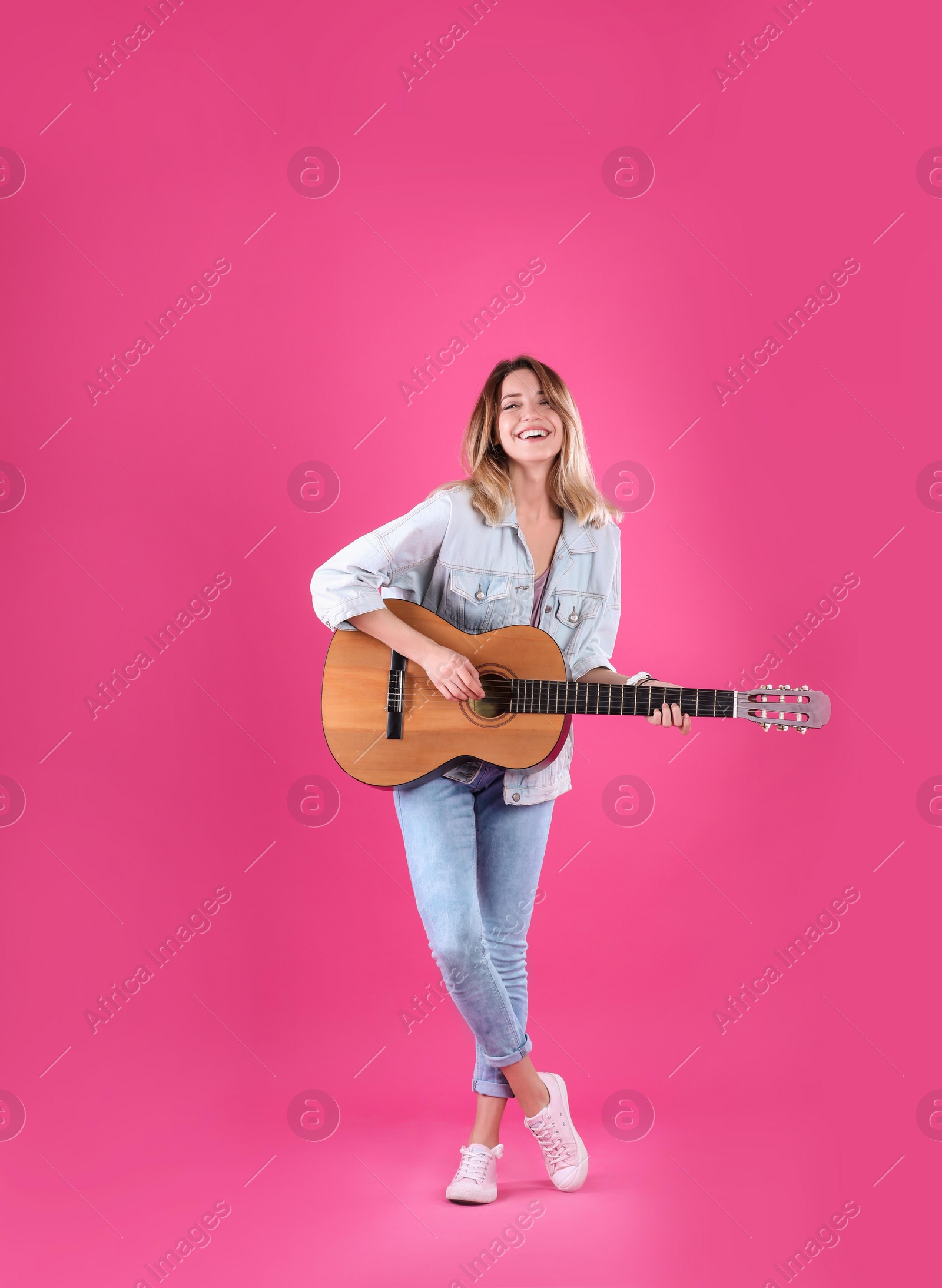 Photo of Young woman playing acoustic guitar on color background