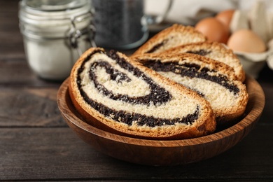 Photo of Pieces of tasty sweet bun with poppy seeds on wooden table