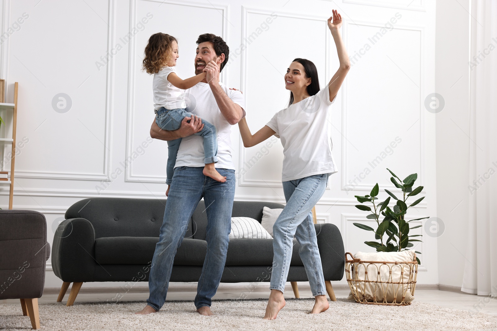 Photo of Happy family dancing and having fun in living room, low angle view