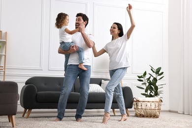 Photo of Happy family dancing and having fun in living room, low angle view