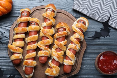 Photo of Cute sausage mummies served on wooden table, flat lay. Halloween party food