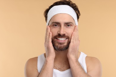 Photo of Washing face. Man with headband on beige background