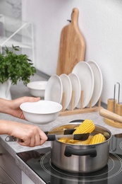 Photo of Woman preparing corn in stewpot on stove, closeup