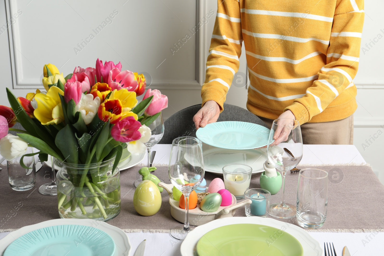 Photo of Woman setting table for festive Easter dinner at home, closeup