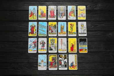 Photo of Tarot cards on black wooden table, flat lay