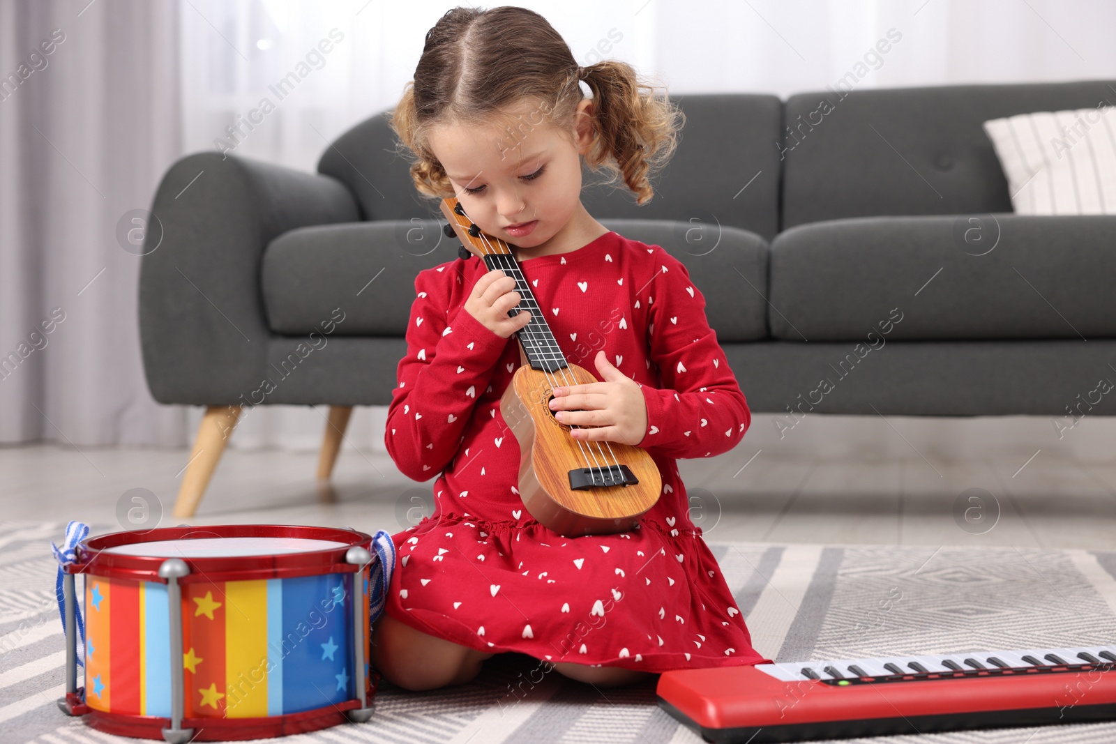 Photo of Little girl playing toy guitar at home