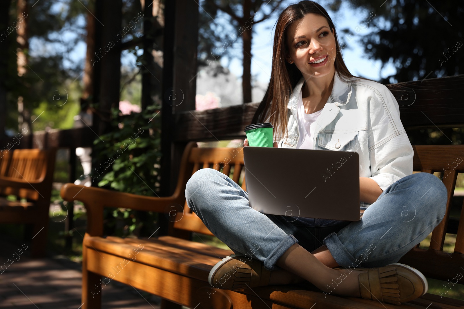 Photo of Beautiful woman with coffee working on laptop in park