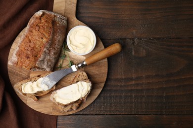 Tasty bread with butter and knife on wooden table, top view. Space for text