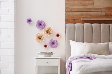 Photo of Stylish bedroom interior with floral decor and white nightstand